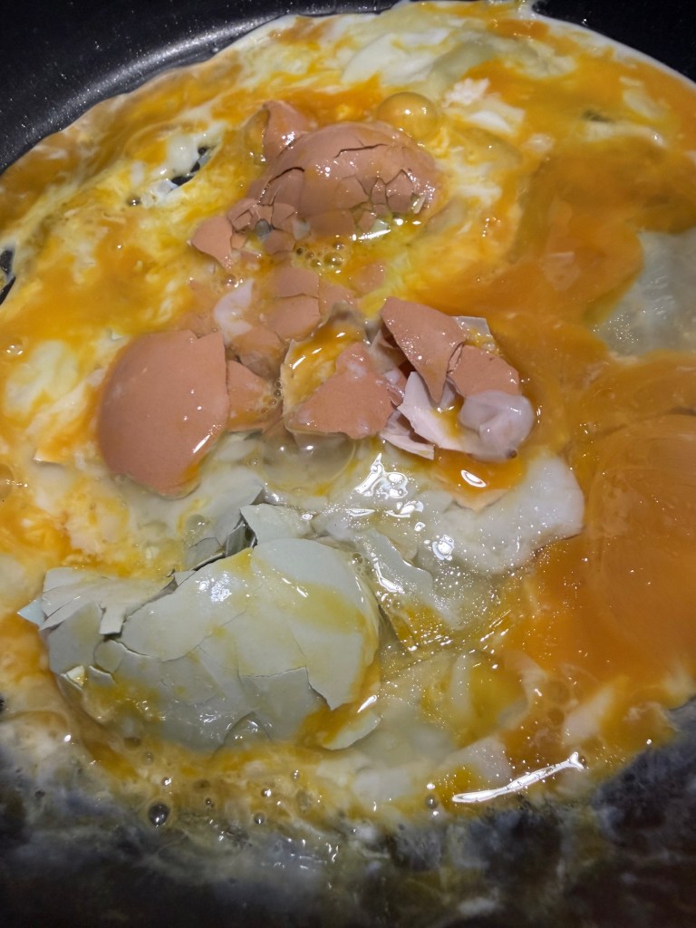 Pan frying eggs and shells all in one pan for the chickens to eat.
